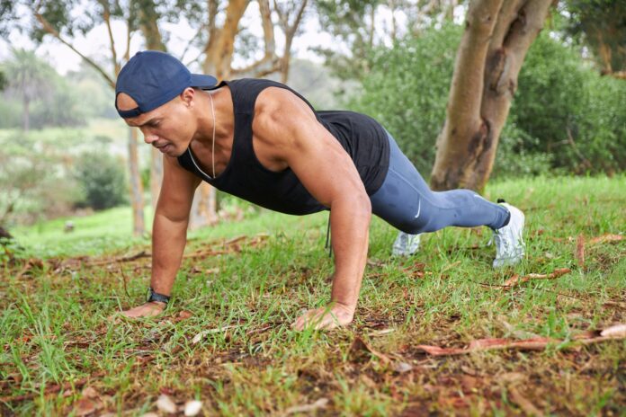 Photo by Sweet Life a man is doing push ups in the grass