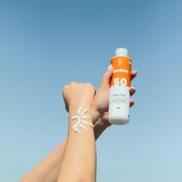 Photo by Onela Ymeri a person holding a bottle of sunscreen in their hand
