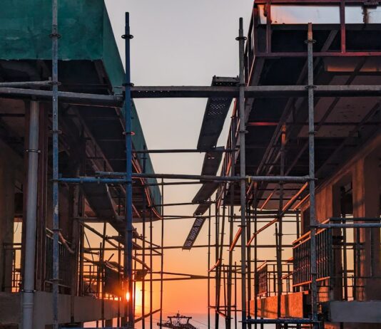 1기 신도시 ‘재건축’ 2027년 첫 삽…도시정비 가이드라인 마련 scaffolding surrounding a building with the sun setting in the background