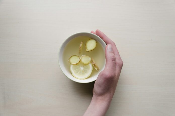 Photo by Dominik Martin person holding white bowl with sliced lime and ginger inside