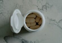 맞춤 영양 보충제, 내 몸에 꼭 맞는 섭취 방법 찾기 Opened bottle of beige pills on marbled surface