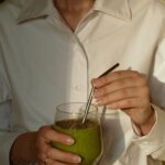한국인의 일상에 스며드는 웰니스 문화, 건강을 일상에서 찾다 person in white button up shirt holding clear drinking glass with green liquid